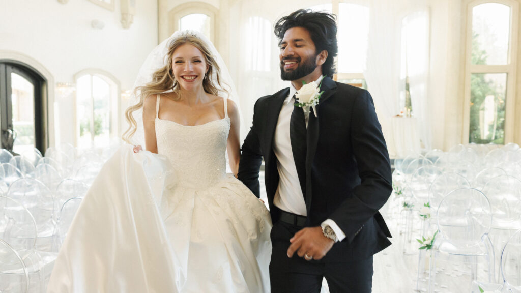 Bride and groom running down the indoor ceremony aisle during a luxury celebration planned with top texas summer wedding tips
