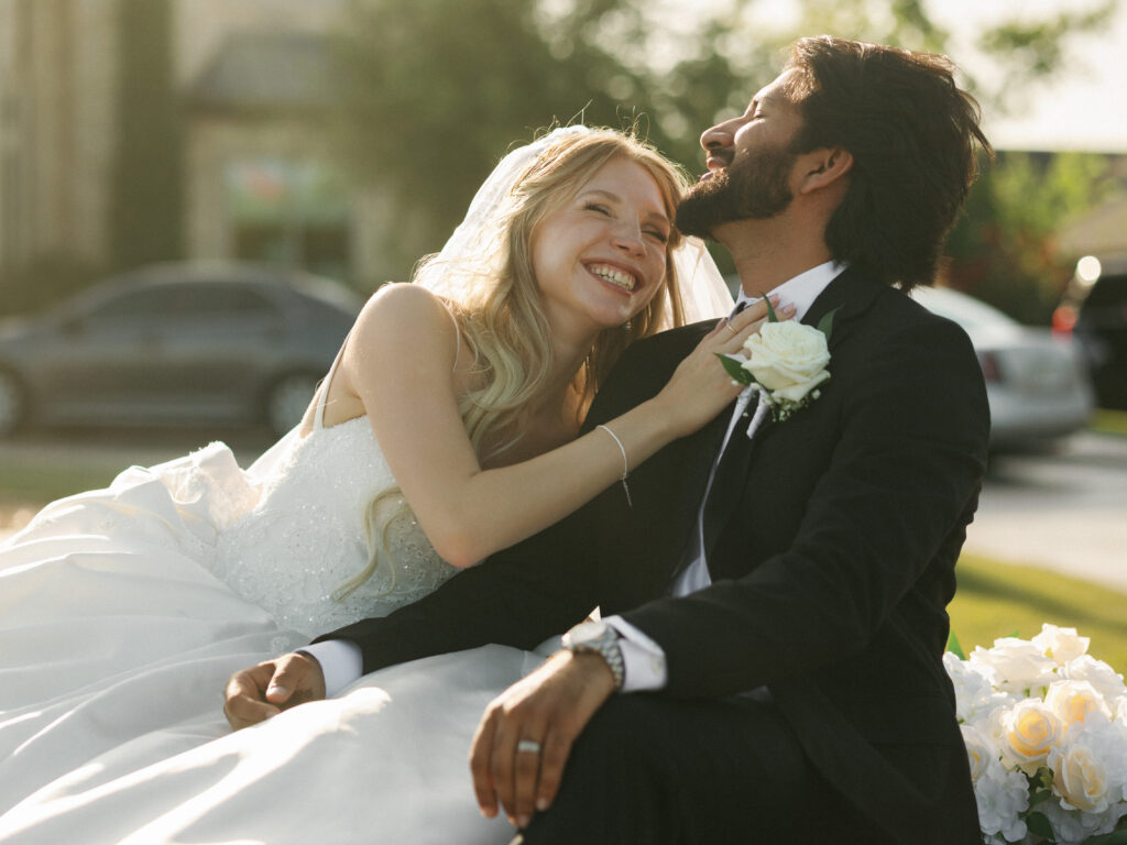 Bride and groom relaxing on a vintage car at sunset during a celebration utilizing professional texas summer wedding tips