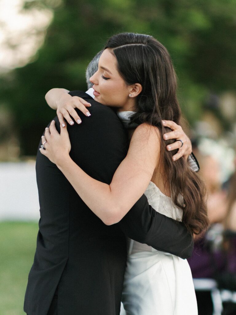 Emotional bride hugging her father during a touching father daughter dance at an outdoor wedding reception