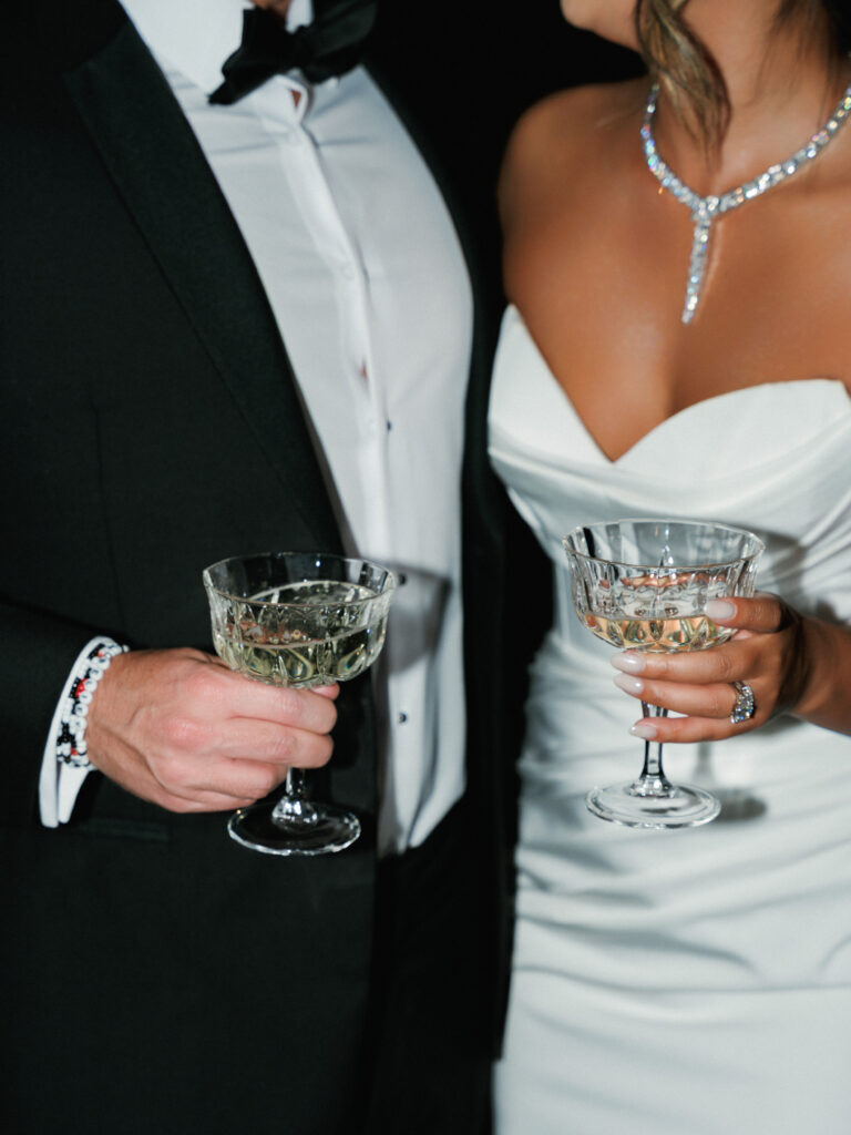 Close up of a luxury bride wearing a diamond necklace and holding vintage champagne glass