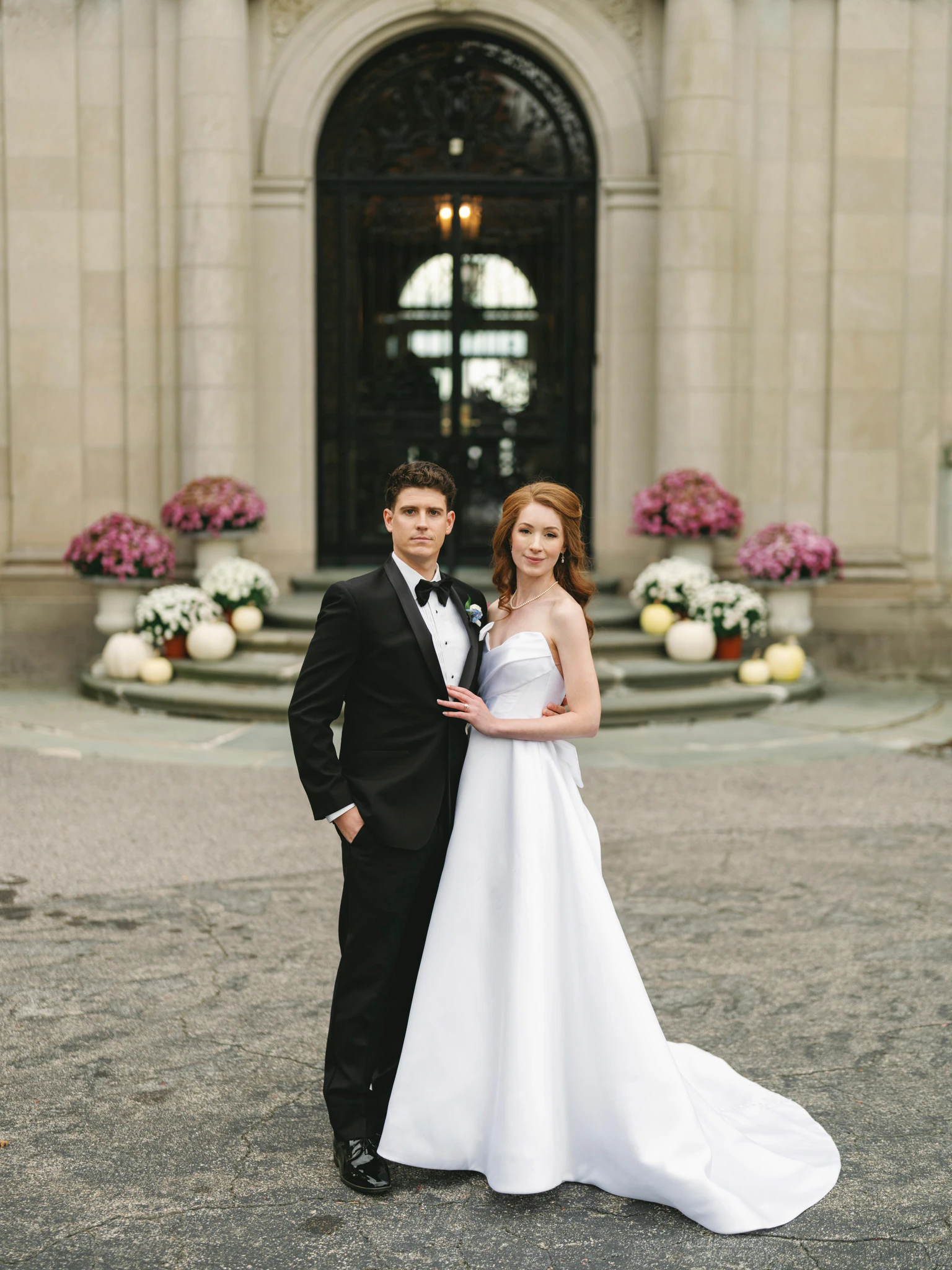 Bride and groom posing in front of a grand stone entrance